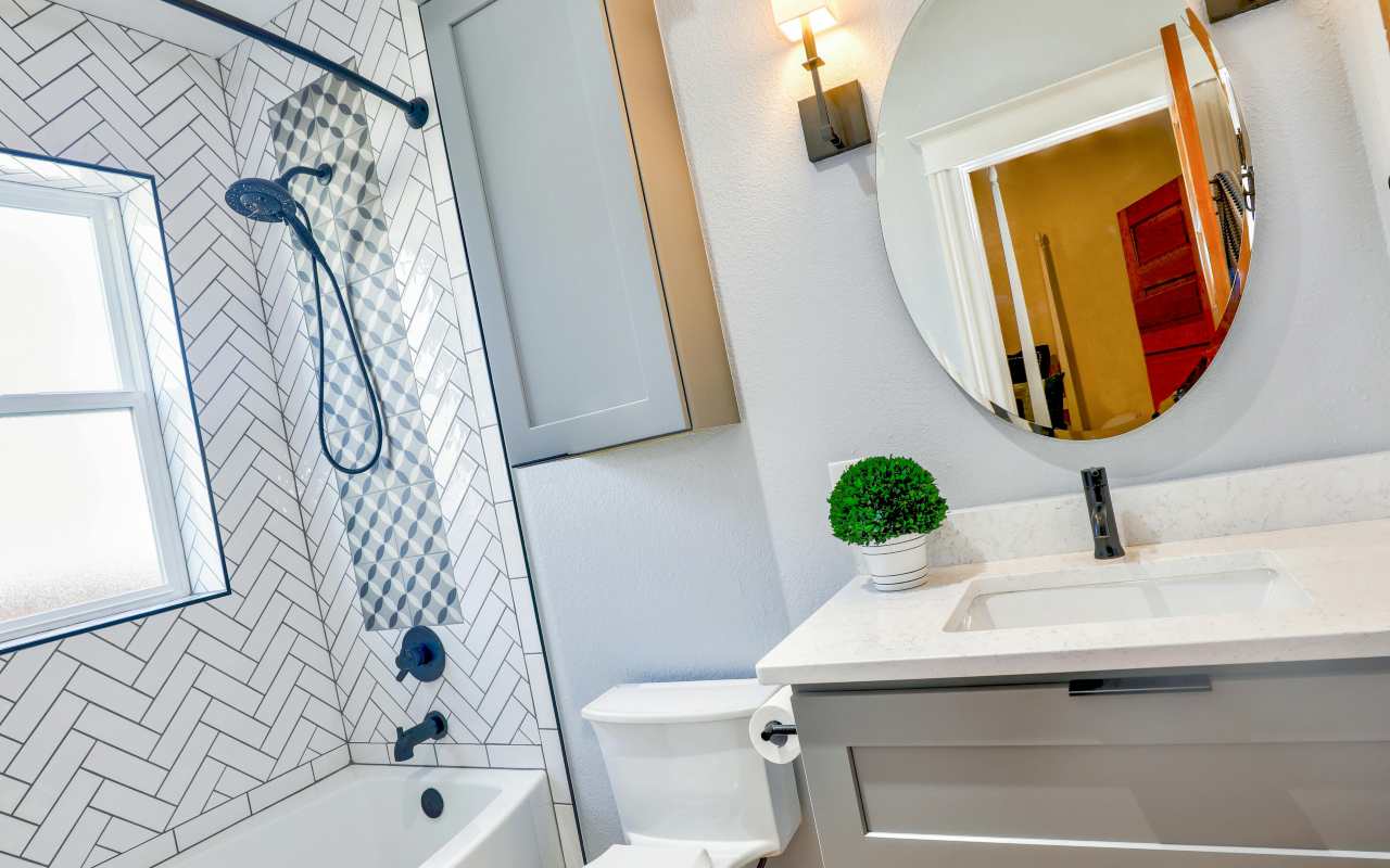 Ovalno ogledalo iznad lavaboa u kupatilu sa kadom